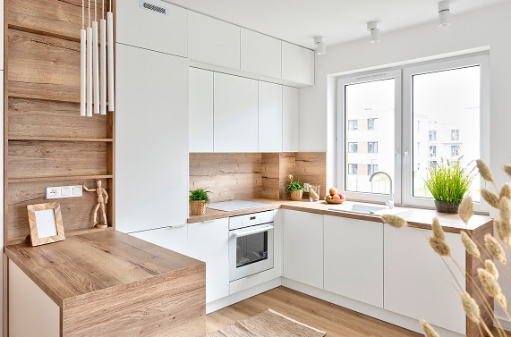 Cuisine moderne blanc et bois : design minimaliste et lumineux Aménagement de cuisine moderne en L avec façades blanches et plans de travail en chêne clair. Évier sous la fenêtre.