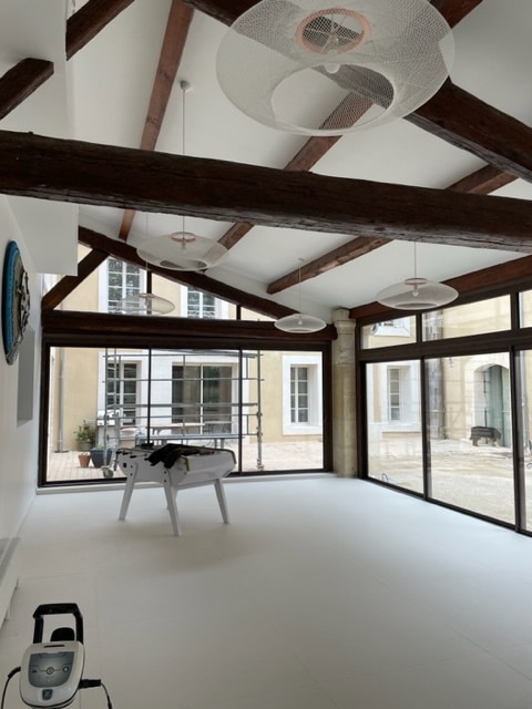 Intérieur moderne sous combles avec poutres apparentes, luminaires design et baby-foot blanc.