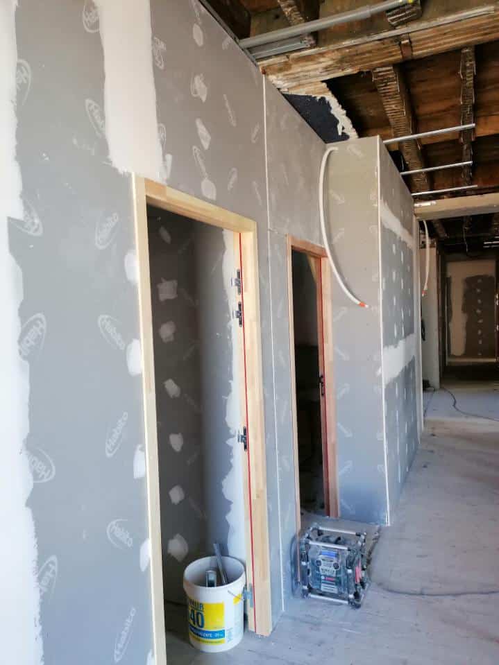 Cloison en plaques Habito avec joints enduits et cadres de portes en bois dans un couloir en rénovation.